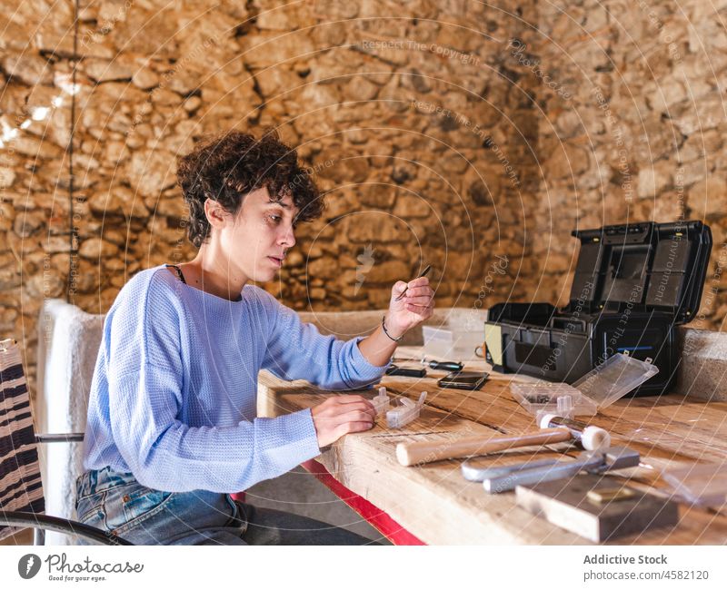 Frau bei der Arbeit mit Edelsteinen in einer Schmuckwerkstatt Handwerkerin Kunstgewerbler Pinzette Juwelier Goldschmied Hobelbank Werkstatt Job professionell