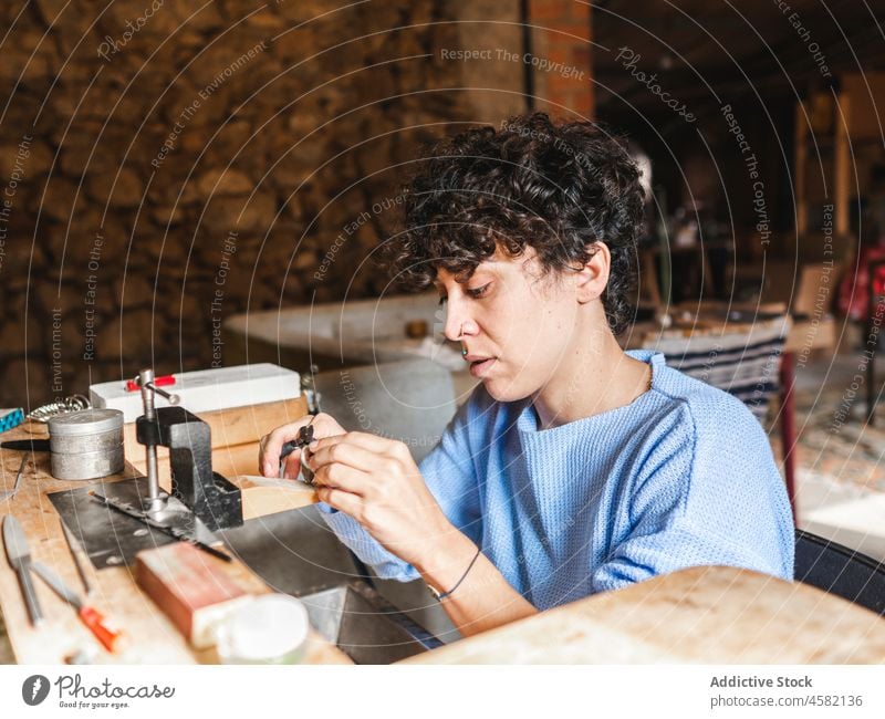 Goldschmiedin bei der Herstellung eines Rings Frau Kunsthandwerker Kunstgewerbler Juwelier Werkstatt Handwerk Zange Prüfstift Hobelbank Arbeit Job hölzern