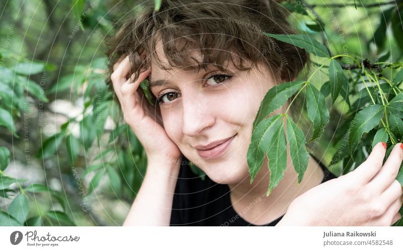 schöne Frau in der Natur mit Blättern vorm Gesicht Leben Lächeln ästhetisch Gefühle Umweltschutz Naturverbundenheit Baum Lebensfreude Glück Fröhlichkeit