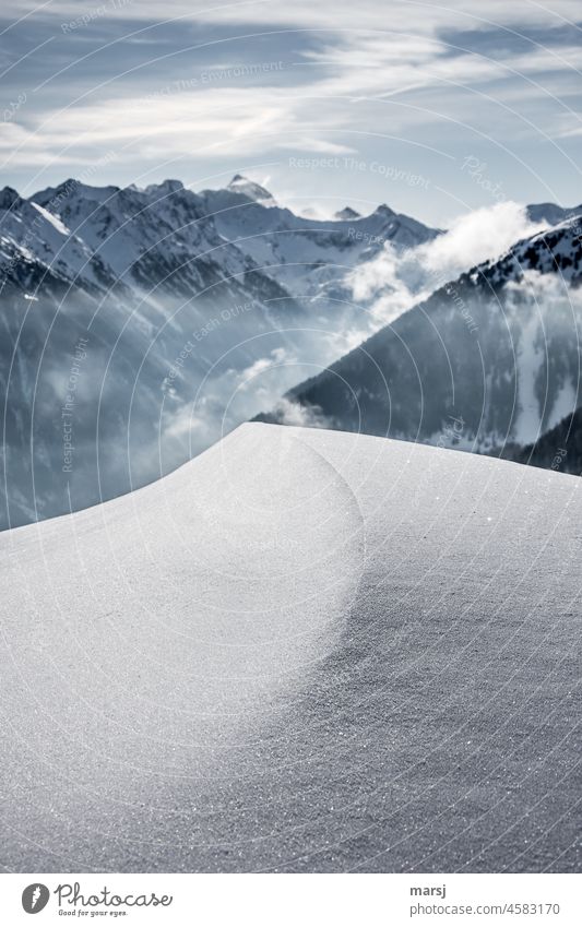 In einer Linie mit dem Bergrücken. Schneewechte mit scharfer Kante. Im Hintergrund schneebedeckte Berge und Nebel. geheimnisvoll Wechte Frost Eis ruhig Winter