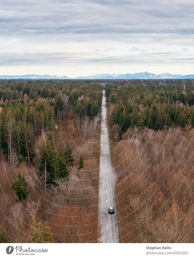 Unterwegs mit dem Auto durch weite Wälder bis hin zu den Bergen im Hintergrund. Ausflug Urlaub PKW Automobile Antenne Berge u. Gebirge Spaß Alpen lang Straße