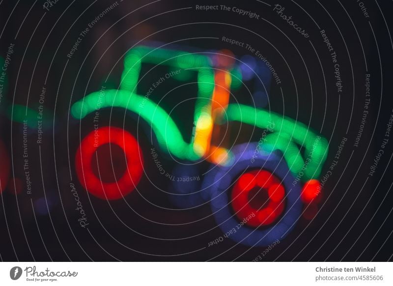Die unscharfe Silhouette eines mit bunten Lichterketten geschmückten Treckers in der Adventszeit Traktor Dekoration & Verzierung Unschärfe defokussiert Nacht
