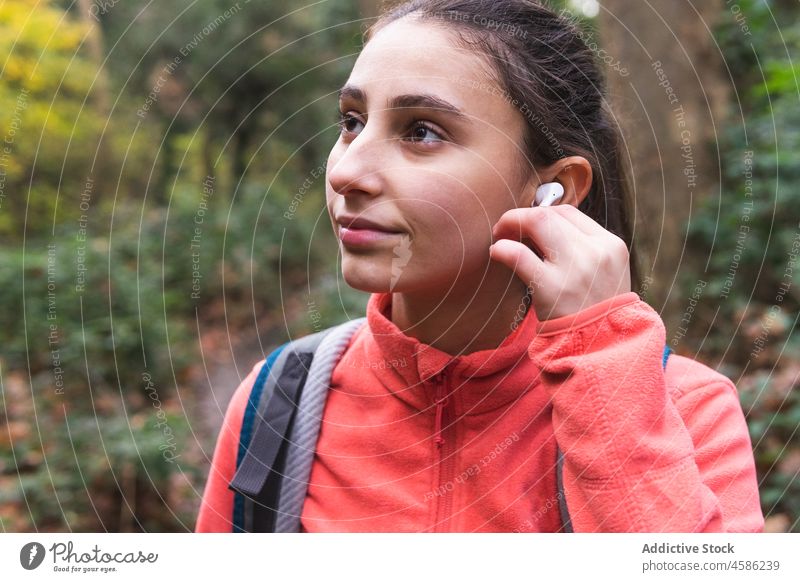 Reisende Frau setzt Kopfhörer in der Natur auf Musik meloman Hobby Wanderer Trekking Abenteuer Wald erkunden Wanderung Pflanze Ausflug Freizeit Reisender