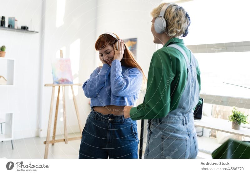 Positive Frauen, die mit Kopfhörern Musik hören Gesang unterhalten Hobby genießen zuhören Freizeit Freund heiter Zusammensein Glück Drahtlos heimwärts modern