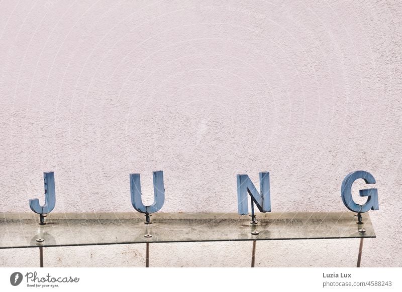 JUNG, Teilansicht einer alten Ladenfassade. Schriftzug, Symbol, Buchstaben. Fassade Name Schriftzeichen Wand Mauer Gebäude grau Schilder & Markierungen Wort