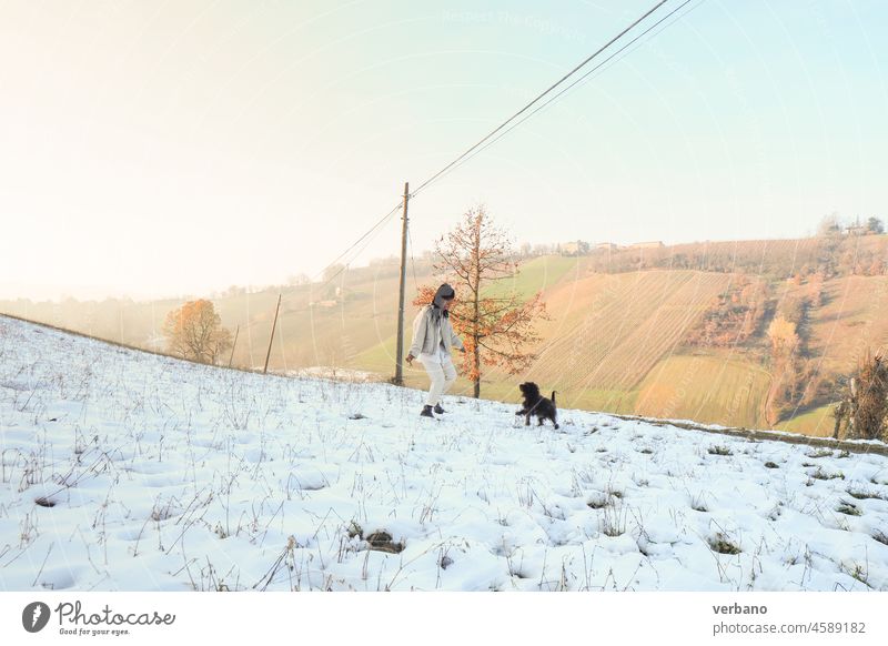 junge Frau spielt mit ihrem schwarzen Hund im Schnee Afrikanisch Rastalocken schön heiter Glück Erwachsener Fröhlichkeit Porträt Mädchen Menschen Lifestyle