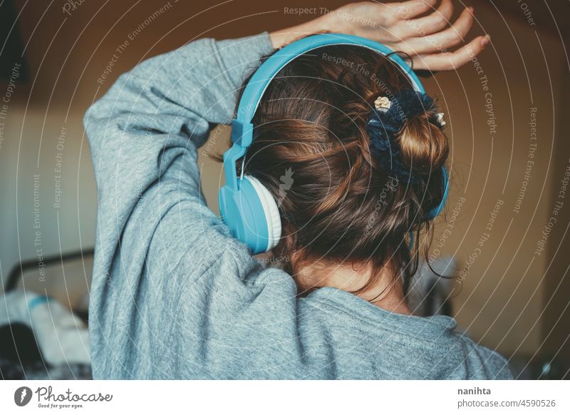 Junge Frau hört Musik und trägt gemütliche Kleidung zuhören Kopfhörer Headset jung Jugend Teenager Musik hören Rücken Ansicht Brötchen Behaarung Frisur Komfort