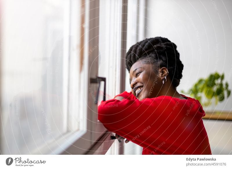 Junge Frau schaut durch ein Fenster schwarz Jahrtausende Hipster im Innenbereich Loft natürlich Erwachsener eine attraktiv gelungen Menschen selbstbewusst