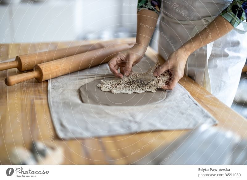 Nahaufnahme einer Kunsthandwerkerin bei der Arbeit an ihrer Töpferware in einer Werkstatt Hände abschließen Konzentration Geduld Topf traditionell Leiste