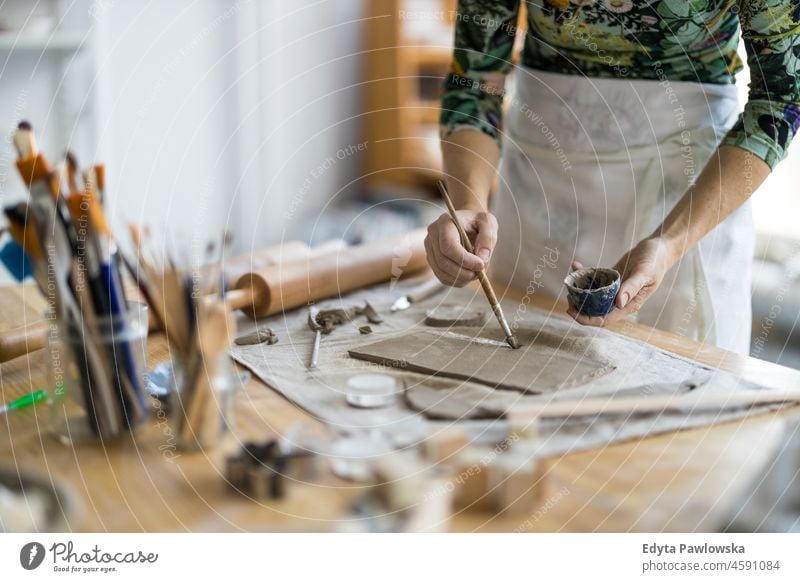 Nahaufnahme einer Kunsthandwerkerin bei der Arbeit an ihrer Töpferware in einer Werkstatt Hände abschließen Konzentration Geduld Topf traditionell Leiste