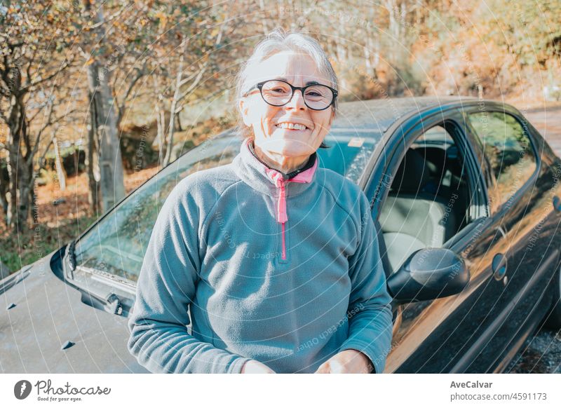 Porträt einer glücklich lächelnden älteren Frau vor dem Auto, die das Autofahren lernt. Sicherheitsfahrt. Lernen neues Hobby, Gewohnheit und Fähigkeit für dieses neue Jahr. Ältere Person, die den Führerschein genehmigt.