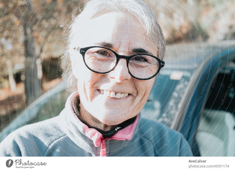 Porträt einer glücklich lächelnden älteren Frau vor dem Auto, die das Autofahren lernt. Sicherheitsfahrt. Lernen neues Hobby, Gewohnheit und Fähigkeit für dieses neue Jahr. Ältere Person, die den Führerschein genehmigt.