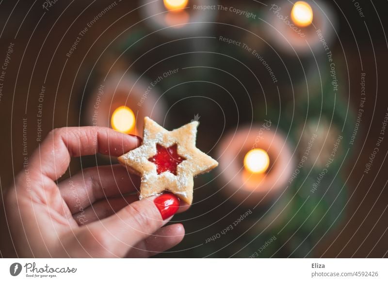 Hand hält Weihnachtsplätzchen über Adventskranz Weihnachten weihnachtlich Stern Plätzchen Weihnachtsgebäck Weihnachten & Advent Kerzenschein Spitzbuben naschen