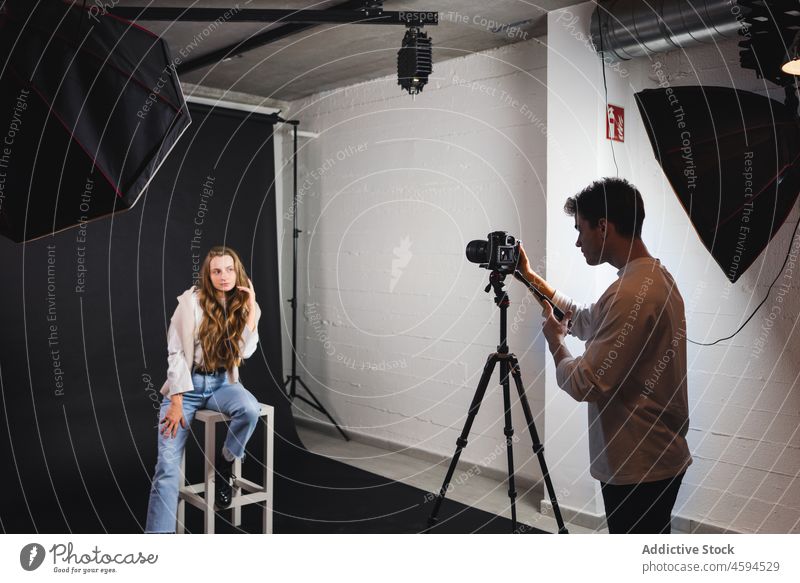 Männliches Foto einer Frau auf einem Stuhl in einem professionellen Studio Mann Fotoapparat Fotograf fotografieren Atelier Gerät trendy Model männlich octabox