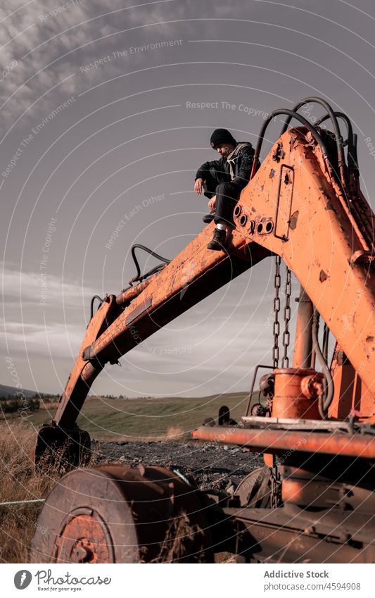 Mann sitzt auf rostigem Bagger in der Natur Industrie Grunge verschlissen Unbewohnt Gerät Umwelt Verlassen Verwesung männlich Korrosion Schiffswrack Abenteuer