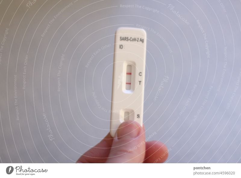 eine Hand hält einen positiven Antigen Schnelltest, Selbsttest für Corona, Covid-19 hoch. Krank, infiziert, Ansteckung corona schnelltest selbsttest krank