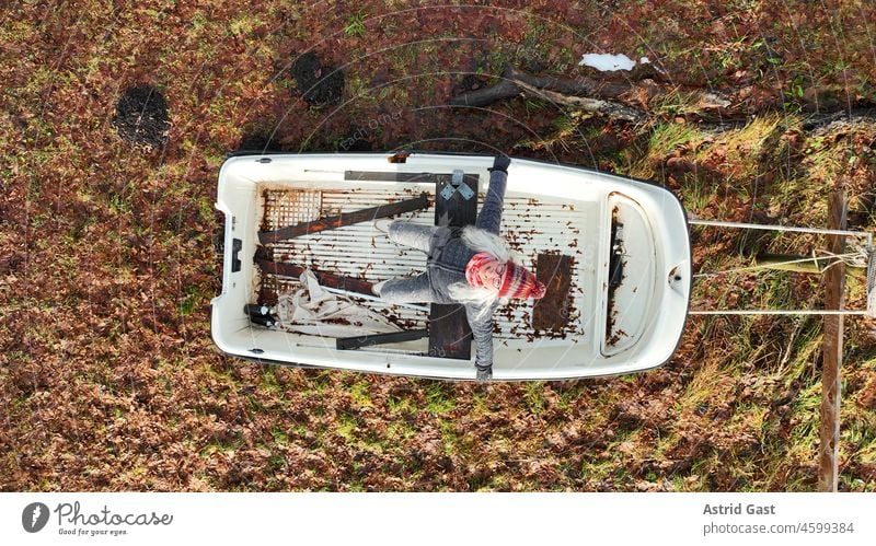 Luftaufnahme mit einer Drohne von einer lachenden Frau die in einem Boot auf Land sitzt luftaufnahme drohnenfoto Stiefel sitzen trockenem lustig Spass Winter