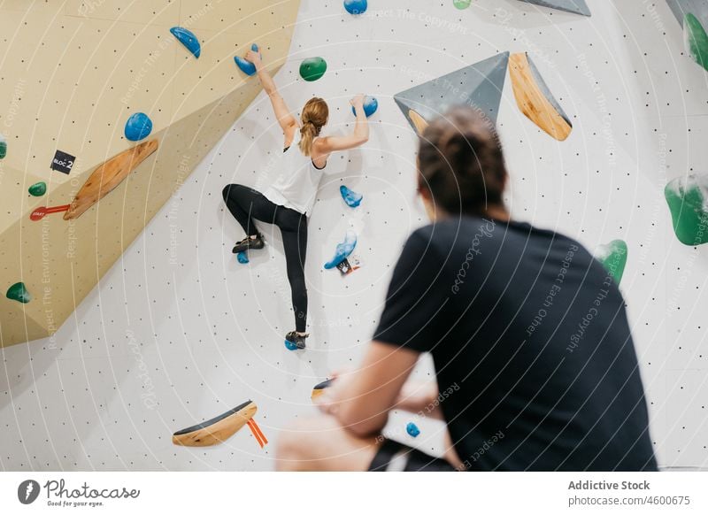 Unbekannter Mann neben kletternder Frau Sportler Aufstieg Training Wand Alpinismus Gesunder Lebensstil Übung üben Alpinist Kletterwand Hobby Aktivität Wellness