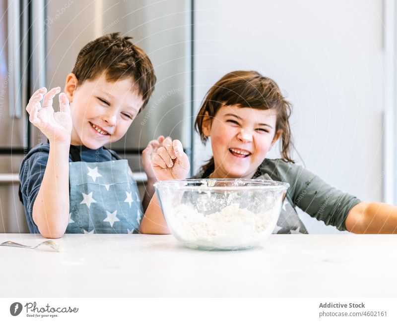 Fröhliche kleine Geschwister beim gemeinsamen Kochen Geschwisterkind Küche mischen kulinarisch Mehl Teigwaren Kinder Zusammensein Küchengeräte Bruder Schwester