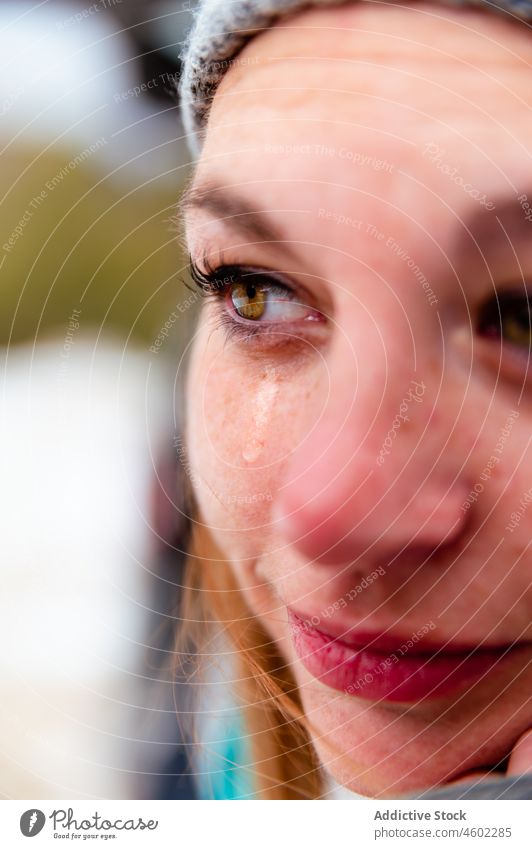 Frau in Mütze und Schal mit Träne in gefrorenem Tag Winter warm Fausthandschuh Oberbekleidung traurig weinen Frost rein warme Kleidung Wolle Strickwaren frieren