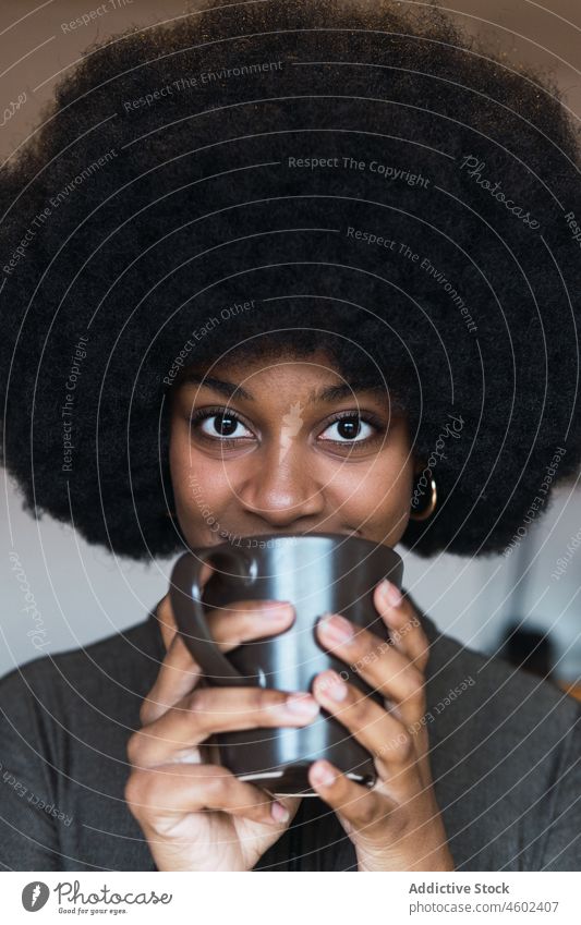 Positive schwarze Frau mit Heißgetränk Tasse Getränk Kaffee Afro-Look feminin Frisur verträumt Lächeln Vorschein Glück charmant brünett attraktiv heiter Inhalt