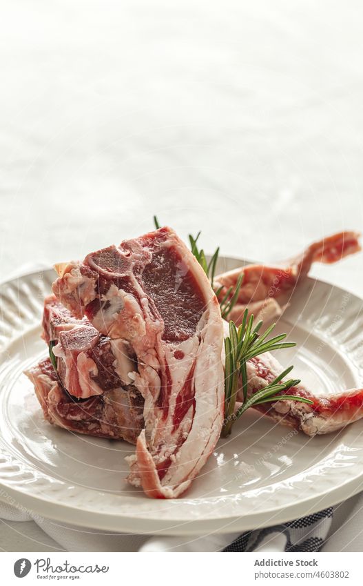 Rohe Lammkoteletts auf einem Teller hacken roh Fleisch dienen Rosmarin ungekocht Lebensmittel Kraut kulinarisch Tisch frisch lecker geschmackvoll Keramik Küche