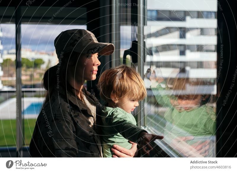 Soldatin mit Sohn schaut aus dem Fenster Mutter Militär Armee Pflicht Junge Mutterschaft beobachten Patriotin Kind niedlich Frau Liebe Zusammensein