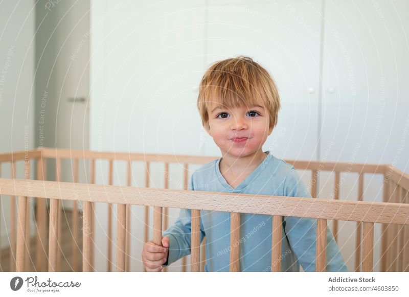 Niedlicher Junge in Krippe stehend Kleinkind Kind Kindheit Babybett Schlafzimmer Kinderbett wach heimisch heimwärts Schlafenszeit Raum Licht niedlich neugierig