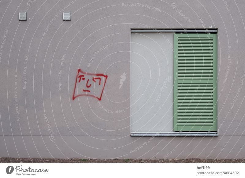 geschlossene Fenster mit lindgrünem Fensterladen und traurigem rotem Grafitto Gesicht Fassade grau Minimalismus minimalistisch Traurigkeit Depression trist