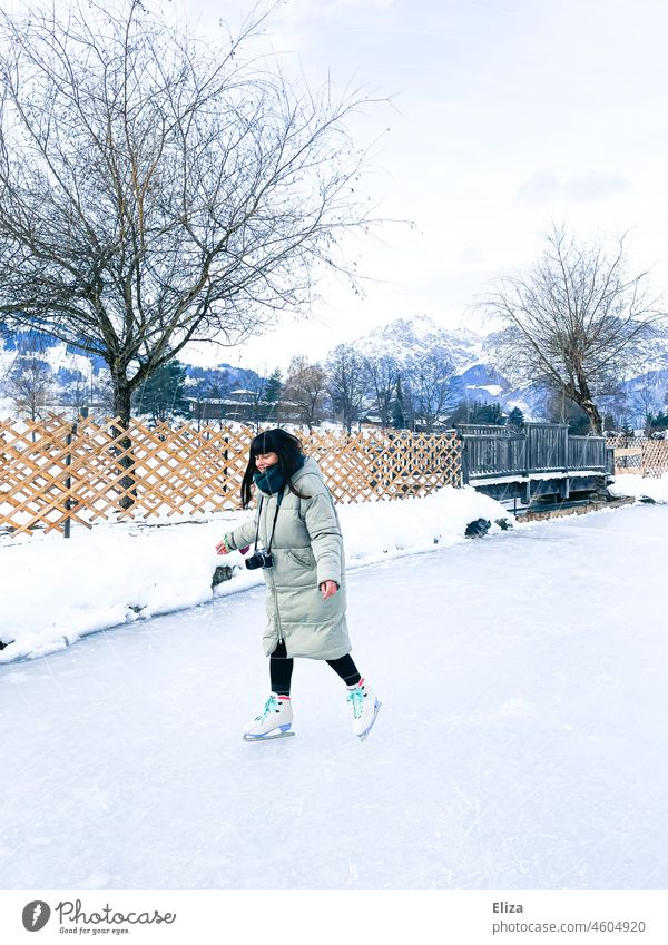 Frau beim Schlittschuhlaufen auf einem zugefrorenen See im Winter Schnee draußen Eislaufen Wintersport Sport Schlittschuhe Winterlandschaft Eisfläche Mensch