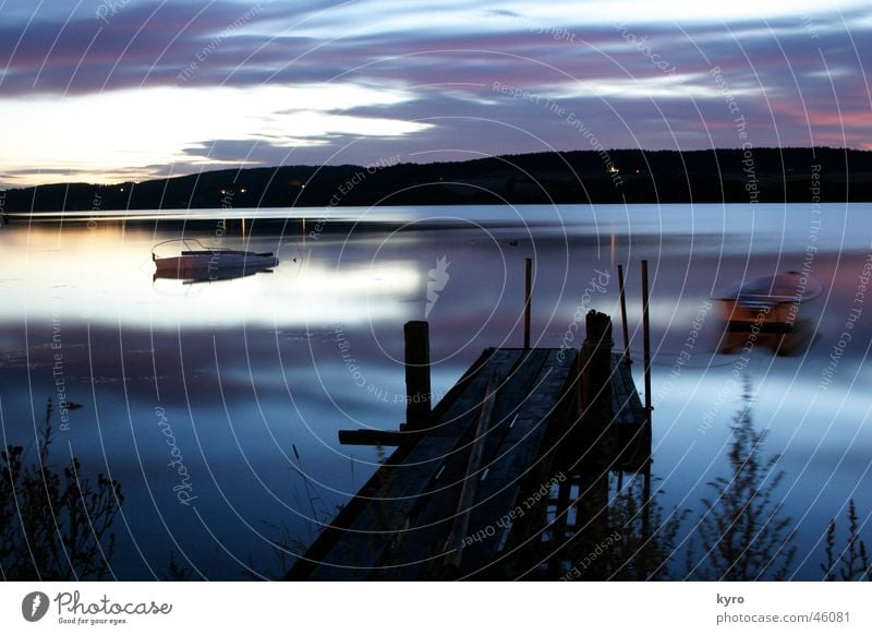 märchensee See ruhig Langzeitbelichtung Blende kalt Wasserfahrzeug Steg Holz Strand Reflexion & Spiegelung Wolken schlechtes Wetter nass dunkel Nacht Glätte