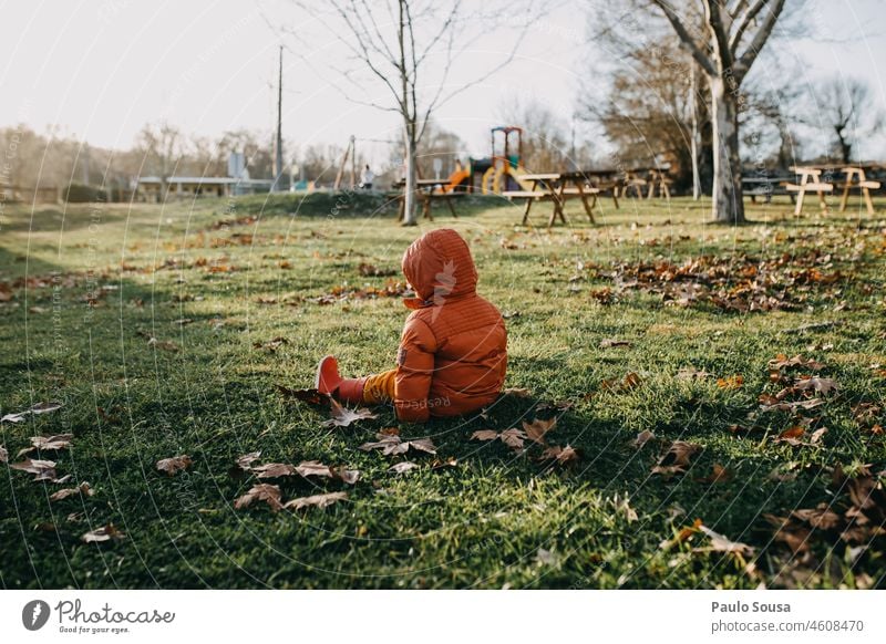 Rückansicht Kind im Gras sitzend Sitzen Kapuze Kapuzenjacke Wutausbruch Jammernde Kapuzenpullover Herbst Farbfoto Mensch Jacke Außenaufnahme Tag 1 1-3 Jahre