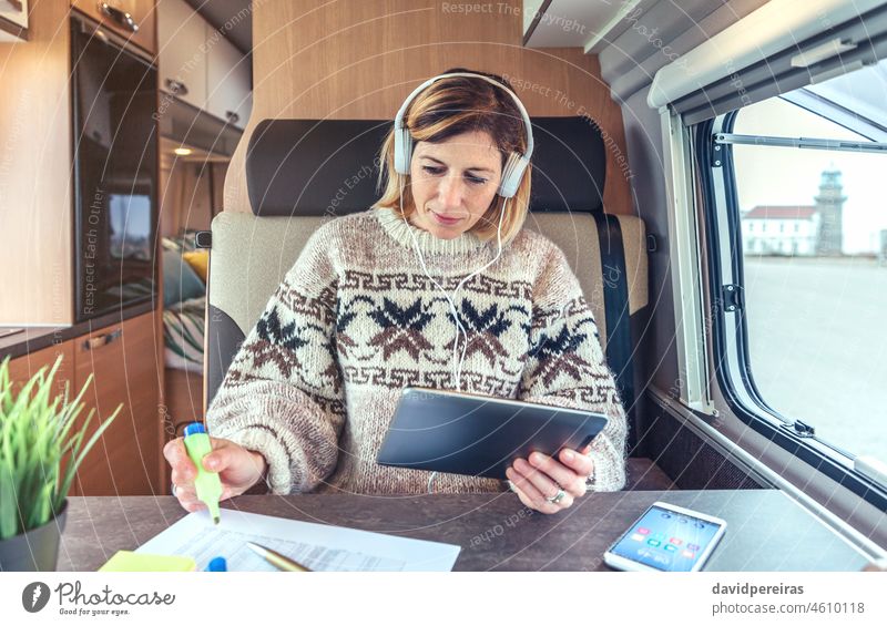 Frau bei der Telearbeit in einem Wohnmobil Tablette Fernarbeit Sitzen Kleintransporter Textmarker Dokumente Ausflug Menschen Wohnwagen arbeiten Business