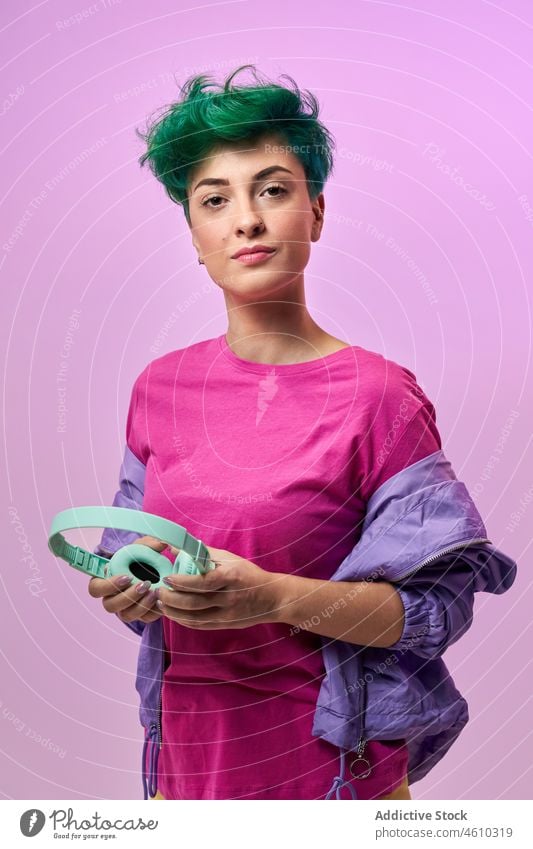 Charismatische Frau mit Kopfhörern im Retro-Outfit meloman Stil tausendjährig 80s Mode Design retro Musik Gesang zuhören Audio Atelier grünes Haar Model