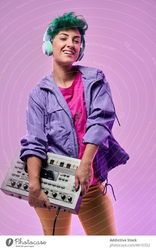 Zufriedene Millennial-Frau mit Kopfhörern und einem Keyboard-Controller spielen Regler komponieren tausendjährig 80s Musik Musiker Stil Mode Design retro Gesang