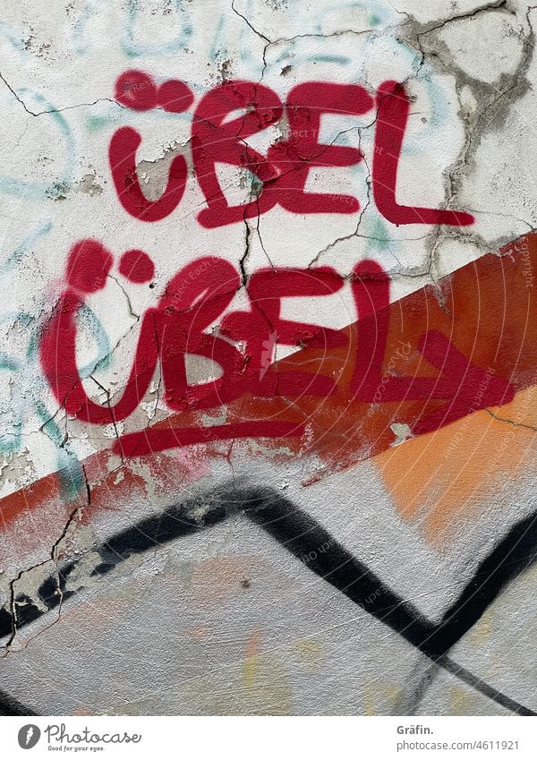 Übel Übel - Putz bröckelt von der Wand auf der ein Graffiti die aktuelle Situation ziemlich genau beschreibt. Kritzelei heruntergekommen Schriftzeichen Farbfoto