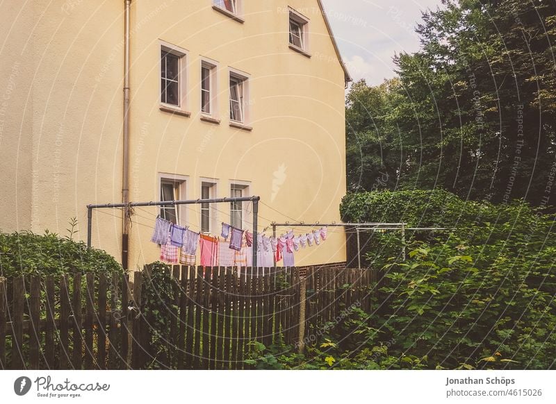 rosa und lila Wäsche auf der Wäscheleine im Garten pink Haus Zaun Fassade wäsche trocknen wäsche aufhängen Wäsche waschen Waschtag Häusliches Leben Haushalt