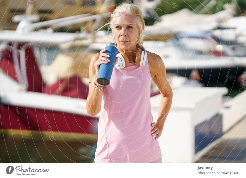 Ältere Frau in Fitnesskleidung trinkt im Freien Wasser aus einer Metall-Fitnessflasche. reif Flasche aussruhen Senior trinken aktiv Training Läufer Gesundheit