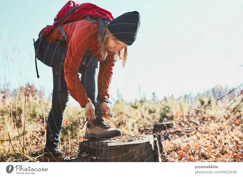 Frau beim Binden von Schnürsenkeln an Wanderschuhen während einer Wanderung im Urlaub. Wanderer mit Rucksack macht Pause beim Wandern Ausflug wandern Abenteuer