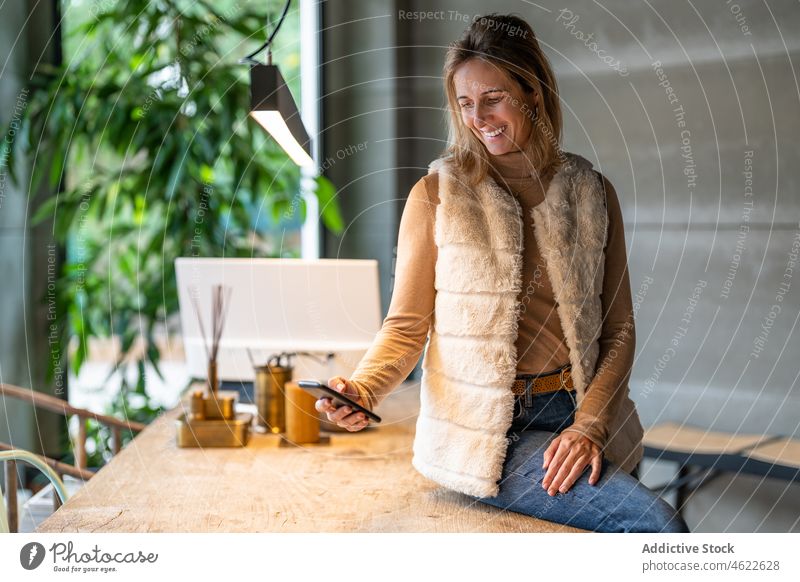 Positive Frau beim Surfen auf dem Smartphone im Büro Browsen online Porträt Arbeitsplatz Stil modern Desktop Unternehmer Arbeiter Business Job positiv Dame