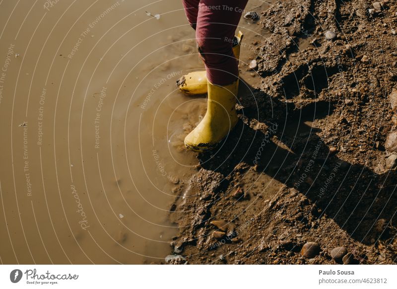 Kind mit gelben Gummistiefeln auf Pfütze Kindheit kleiner Abschnitt Mensch Farbfoto Kindheitserinnerung authentisch Fröhlichkeit Tag mehrfarbig Spielen