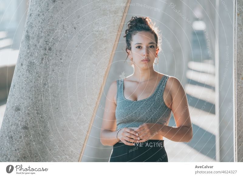 Junge arabische afrikanische Frau auf dem Training Sport tragen Leggins Porträt schaut ernst direkt in die Kamera während einer Trainingseinheit. Ernst in die Kamera, junge Athleten städtischen Stadt Hintergrund Kopie Raum