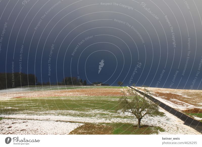 Bedrohlich dunkler Himmel über einer Winterlandschaft mit Schnee bei Tauwetter im Klimawandel bedrohlich dunkel Wetter gewitter Sturm Ackerland Unwetter