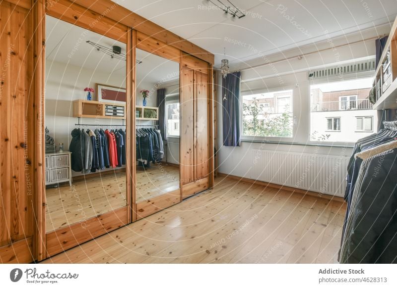 Geräumiges Ankleidezimmer mit Kleiderschrank und Holzboden Innenbereich Appartement Spiegel Stoff Ablage Design geräumig Bekleidung Reflexion & Spiegelung