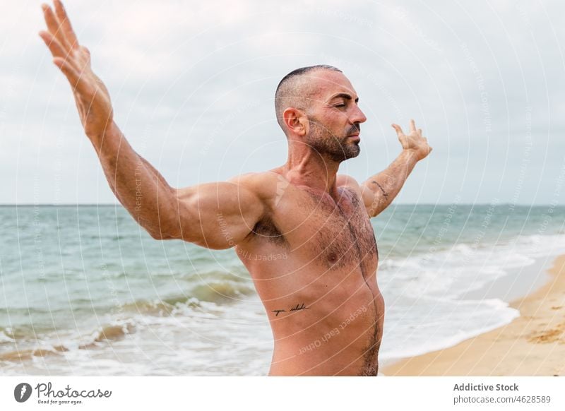 Mann ohne Hemd mit ausgebreiteten Armen am Strand nackter Torso MEER Training Wasser Ufer Augen geschlossen Gesunder Lebensstil Wohlbefinden sportlich muskulös