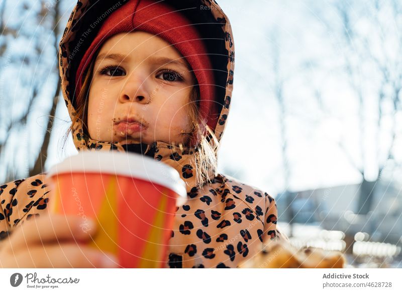 Nettes Mädchen mit Getränk zum Mitnehmen an einem Wintertag Kind Keks Imbissbude Heißgetränk Straße Großstadt kalt Kindheit Dessert trinken Oberbekleidung