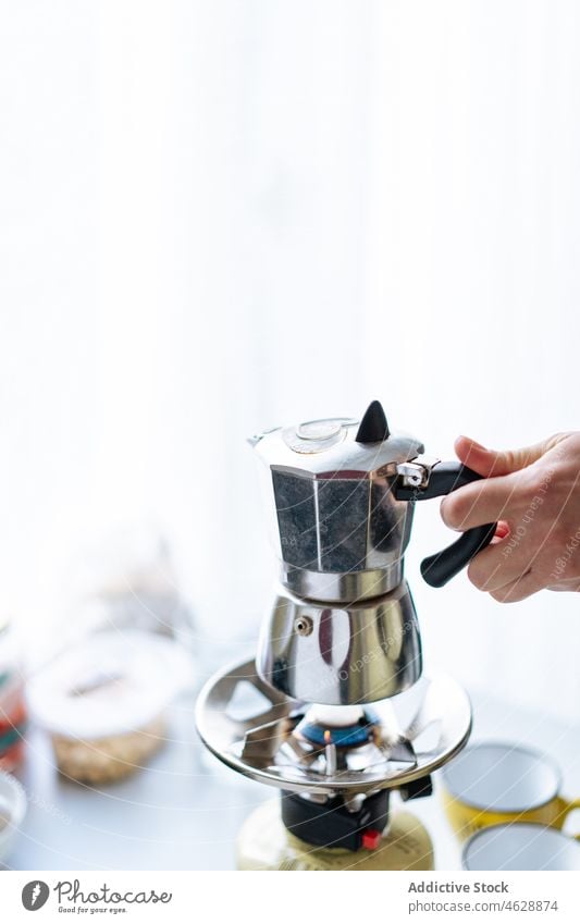 Anonyme Person mit Moka-Kanne in heller Küche Moka-Topf Hand Kaffeemaschine Geysir Herd brauen Vorrichtung modern Küchengeräte Gas Gerät rostfrei Stahl Metall