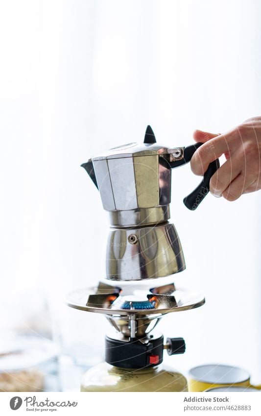 Anonyme Person mit Moka-Kanne in heller Küche Moka-Topf Hand Kaffeemaschine Geysir Herd brauen Vorrichtung modern Küchengeräte Gas Gerät rostfrei Stahl Metall