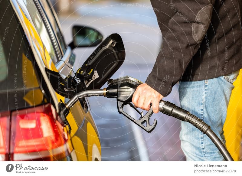 Hand mit Zapfpistole an einer Tankstelle Auto Autokraftstoff Autogas Benzin tanken Biokraftstoff biosprit co2 Diesel e10 e5 elektrisch Energie Ethanol besetzen