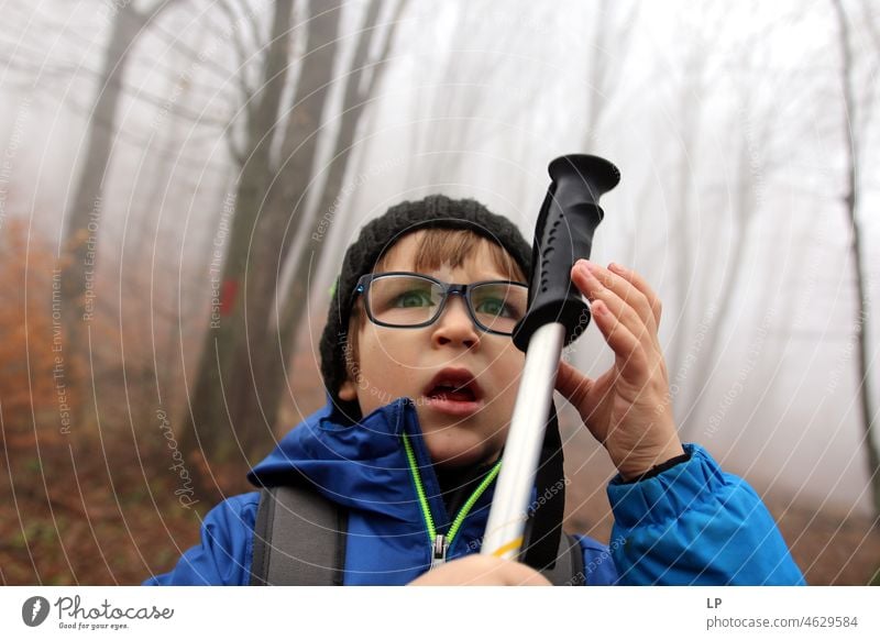 das Gesicht eines schönen Kindes, das eine Brille trägt, wütend dreinschaut und einen Stock in der Hand hält Stress Frustration Zukunftsangst Verbote Grimasse